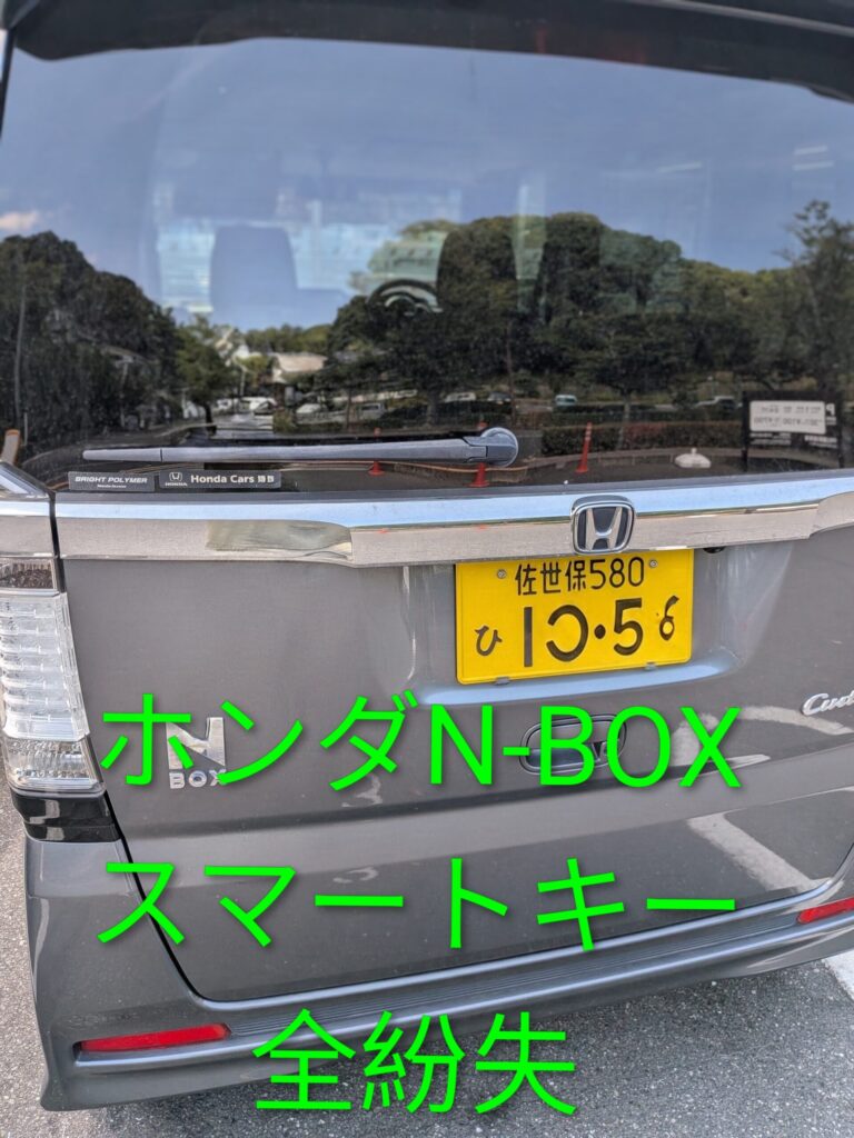Rear view of a gray Honda N-BOX with a yellow license plate; large bright green Japanese text overlays the tailgate.